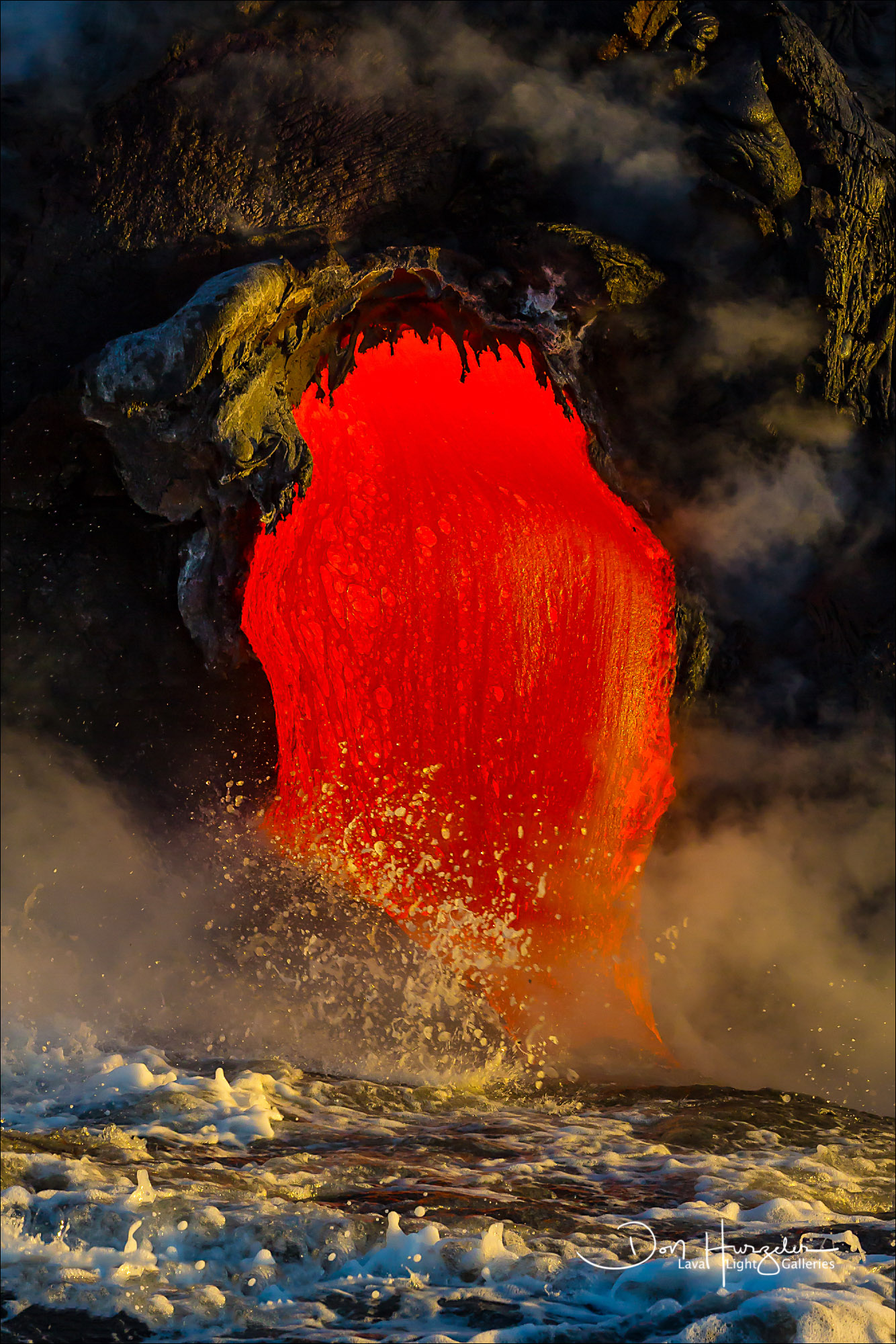 A huge amount of liquid lava pouring from a lava tube and into the sea.